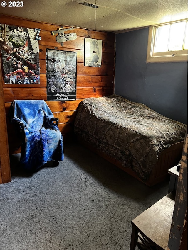 carpeted bedroom with a textured ceiling and wood walls