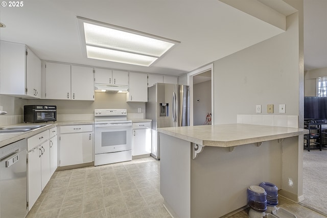 kitchen with white cabinets, appliances with stainless steel finishes, sink, kitchen peninsula, and a breakfast bar