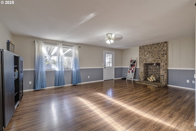 unfurnished living room featuring a textured ceiling, dark hardwood / wood-style floors, and a fireplace