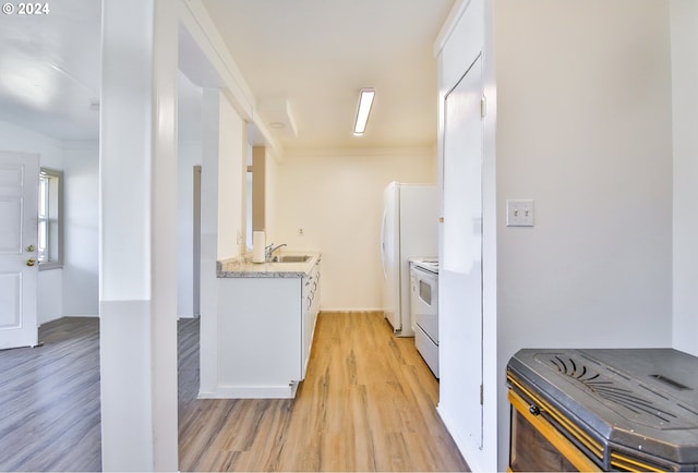 kitchen with white cabinetry, white appliances, light wood-type flooring, and a sink