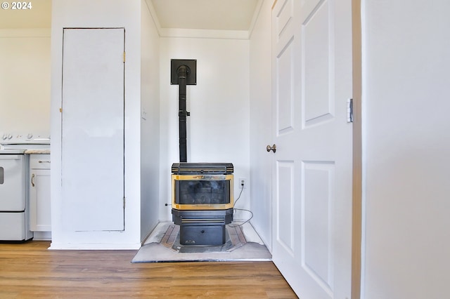 room details featuring ornamental molding, white electric stove, a wood stove, and wood finished floors