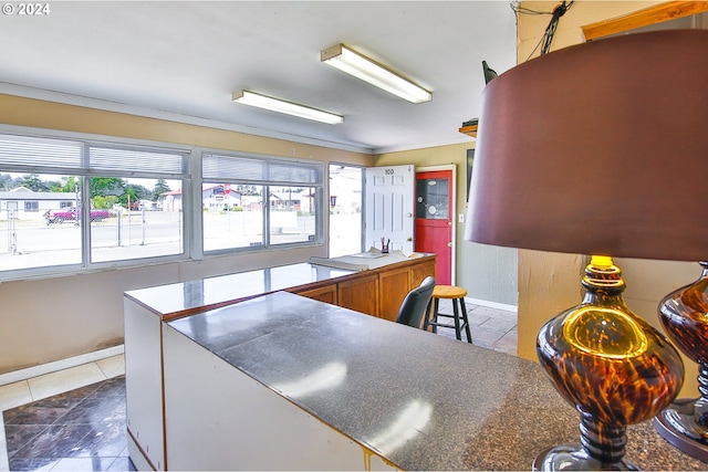 kitchen featuring dark tile patterned flooring and crown molding