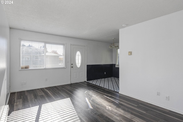 foyer featuring a textured ceiling, dark hardwood / wood-style flooring, and an inviting chandelier