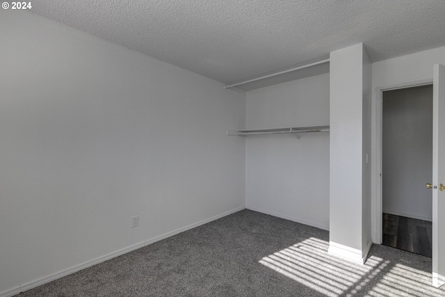 unfurnished bedroom featuring a closet, dark carpet, and a textured ceiling