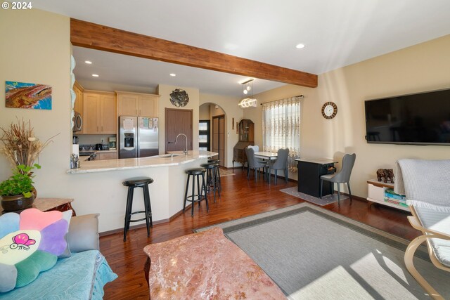 living room featuring beamed ceiling, dark hardwood / wood-style flooring, and sink