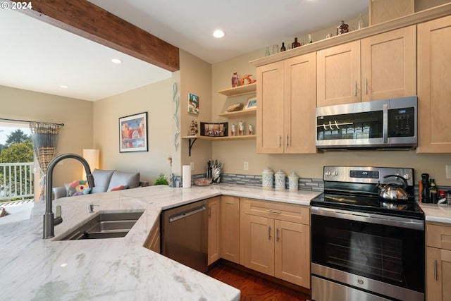 kitchen with sink, light stone counters, kitchen peninsula, stainless steel appliances, and light brown cabinets