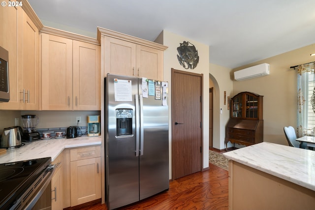 kitchen with a wall mounted air conditioner, light brown cabinets, and appliances with stainless steel finishes