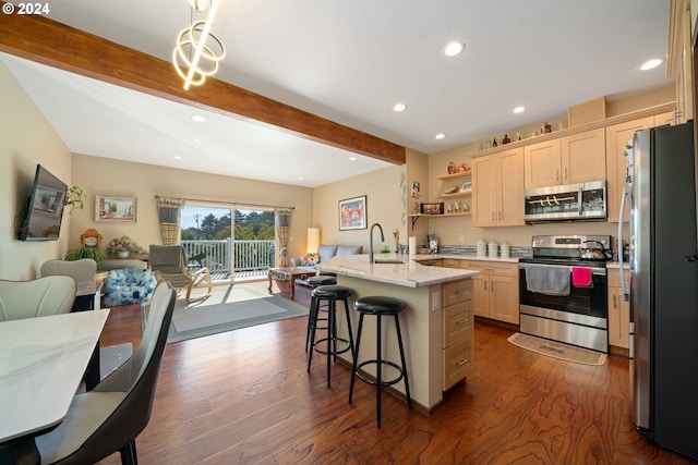 kitchen featuring appliances with stainless steel finishes, a kitchen breakfast bar, an island with sink, beam ceiling, and light stone countertops