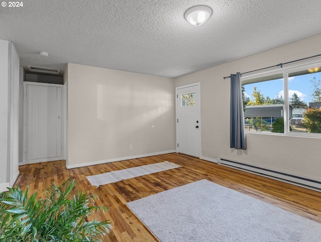 unfurnished room featuring hardwood / wood-style floors, a baseboard radiator, and a textured ceiling