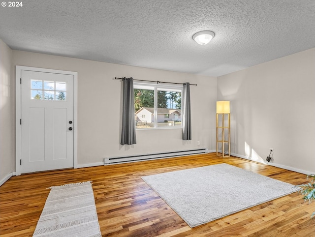 entrance foyer with hardwood / wood-style flooring, baseboard heating, and a textured ceiling