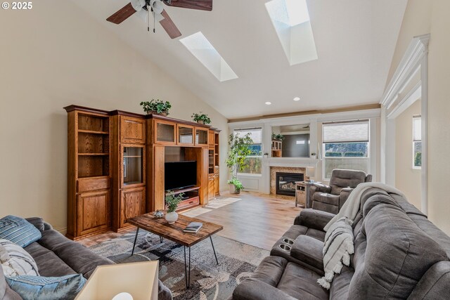 living room featuring a skylight, light wood-type flooring, high vaulted ceiling, and ceiling fan