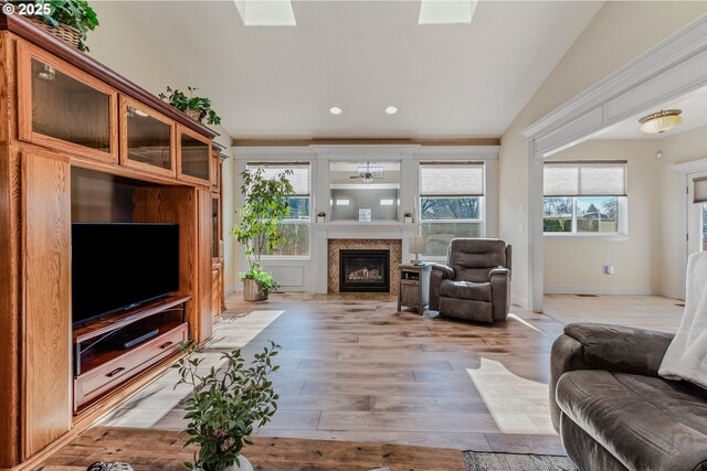 living room with light hardwood / wood-style floors and vaulted ceiling with skylight