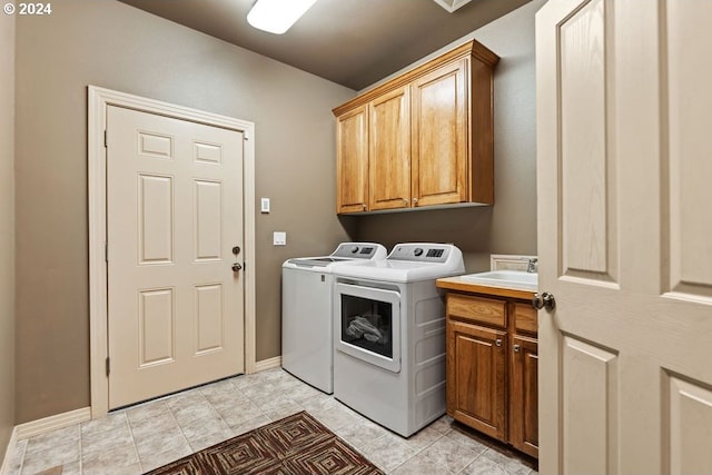 laundry room featuring washing machine and clothes dryer, light tile patterned floors, and cabinets