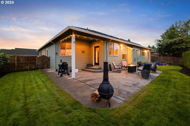 back house at dusk with a patio area, a fire pit, and a lawn