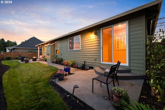 back house at dusk featuring a patio and a yard