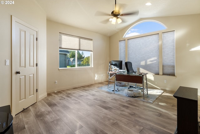 office space featuring vaulted ceiling, a healthy amount of sunlight, light hardwood / wood-style flooring, and ceiling fan