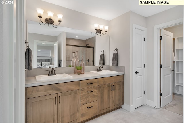 bathroom with vanity, an inviting chandelier, and a shower with shower door