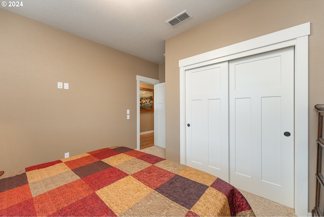 carpeted bedroom with a closet and a textured ceiling