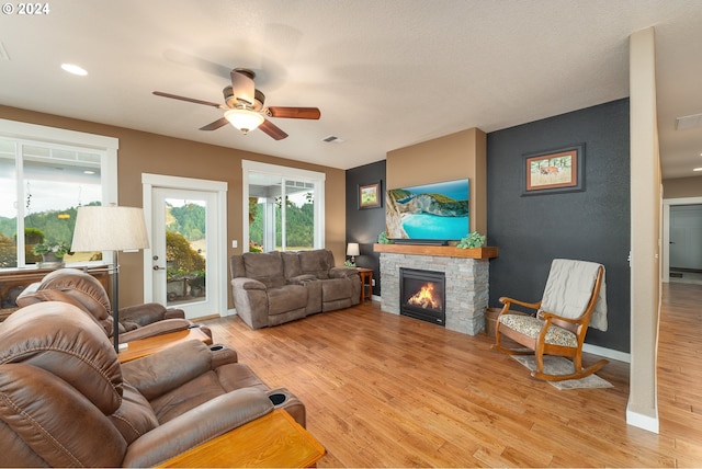 living room featuring ceiling fan, light hardwood / wood-style flooring, and a fireplace