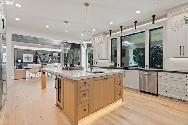 kitchen with pendant lighting, sink, a barn door, a center island with sink, and appliances with stainless steel finishes