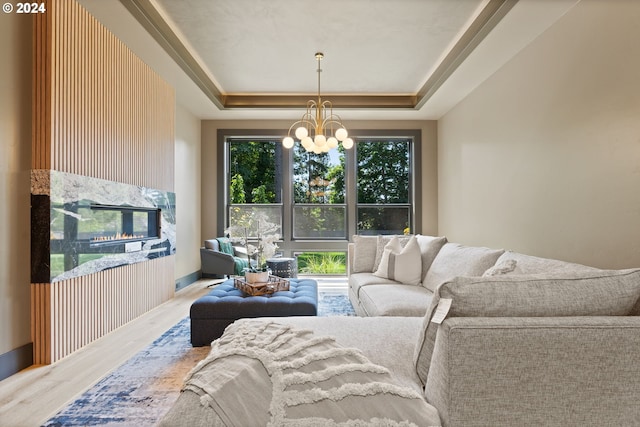 living room with a notable chandelier, a raised ceiling, hardwood / wood-style floors, and a wealth of natural light