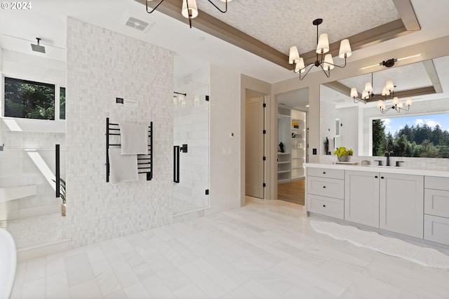 bathroom with tile walls, vanity, a tray ceiling, a shower with door, and a chandelier