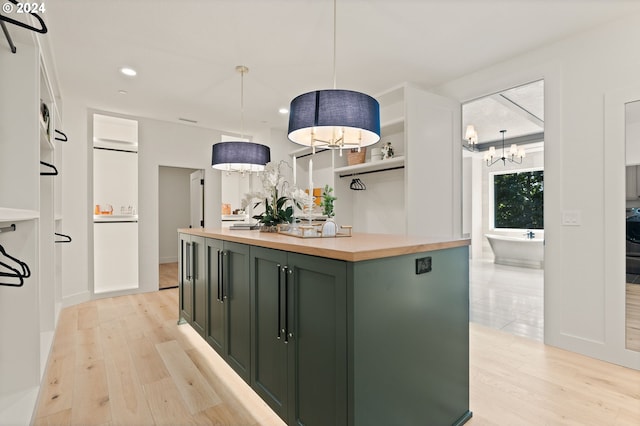 kitchen featuring a center island, green cabinetry, butcher block counters, light hardwood / wood-style flooring, and decorative light fixtures