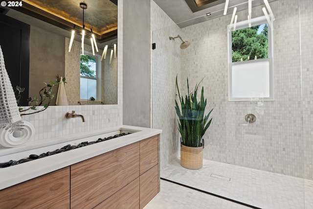 bathroom with vanity, a tile shower, tasteful backsplash, and a wealth of natural light