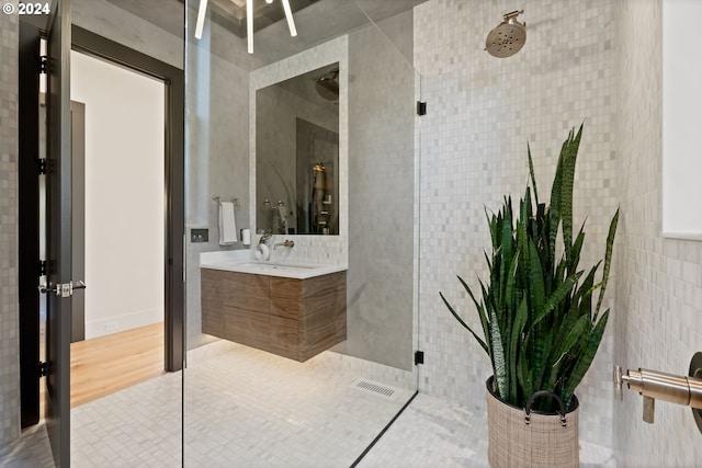 bathroom featuring walk in shower, hardwood / wood-style flooring, vanity, and tile walls