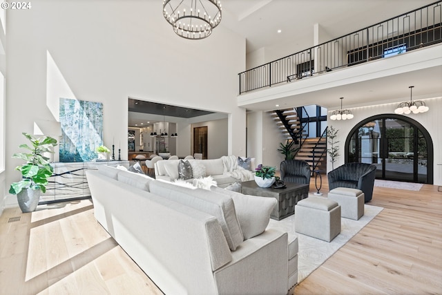 living room featuring light hardwood / wood-style flooring, a towering ceiling, and a chandelier