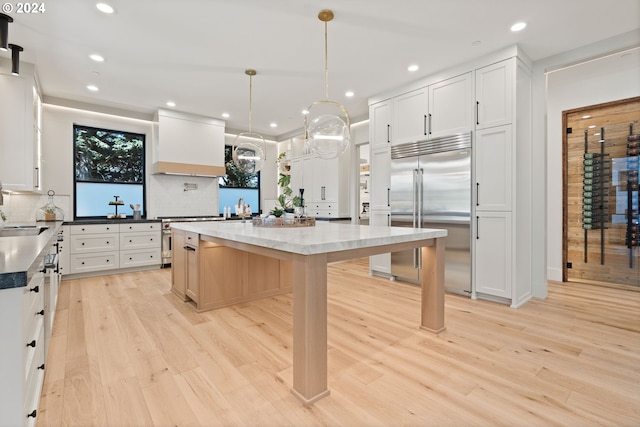 kitchen featuring stainless steel built in refrigerator, light wood-type flooring, and pendant lighting