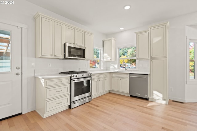 kitchen with light wood-type flooring, stainless steel appliances, sink, and plenty of natural light