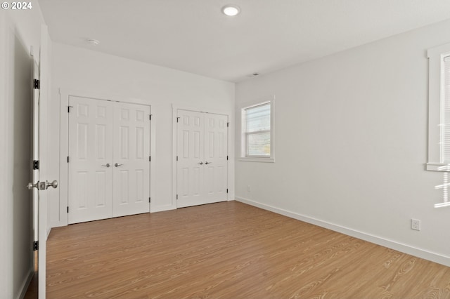 unfurnished bedroom with multiple closets and light hardwood / wood-style flooring