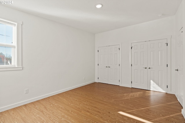 unfurnished bedroom with hardwood / wood-style flooring and two closets