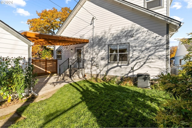 back of property featuring central AC unit and a lawn