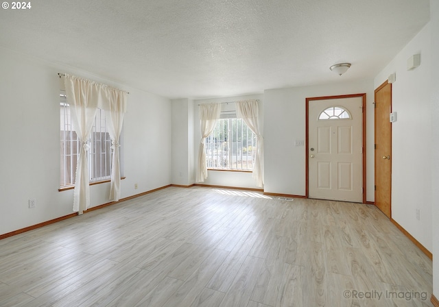 entrance foyer with a textured ceiling and light hardwood / wood-style floors