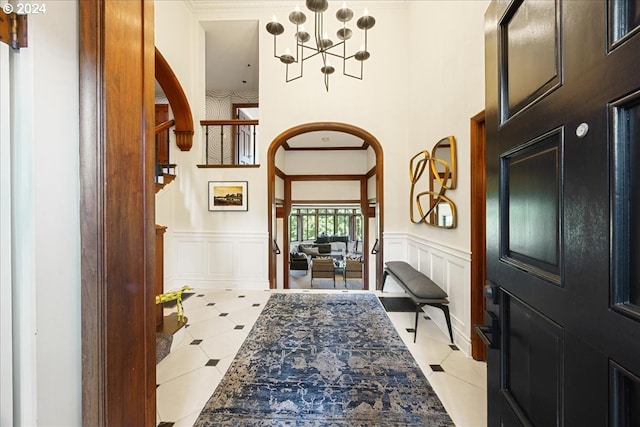 tiled entryway with a notable chandelier and ornamental molding