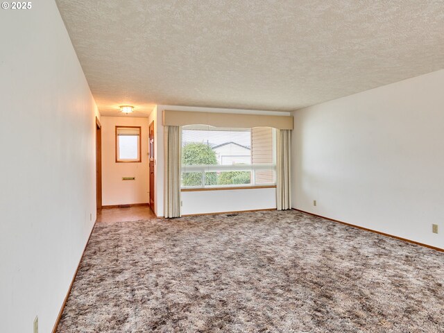 empty room with a chandelier, a textured ceiling, and dark colored carpet