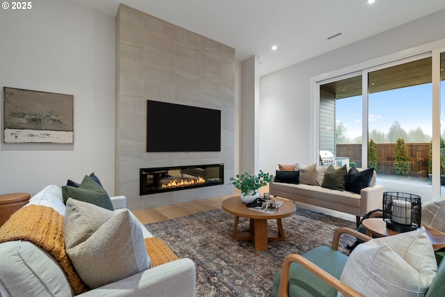 living area featuring recessed lighting, visible vents, a tiled fireplace, and wood finished floors