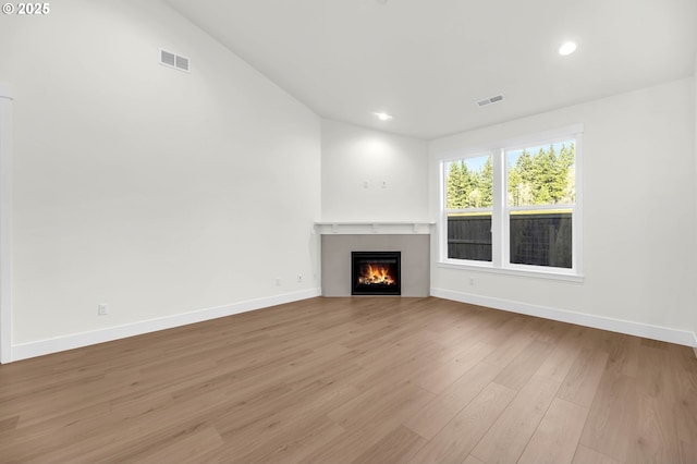 unfurnished living room featuring vaulted ceiling and light hardwood / wood-style floors