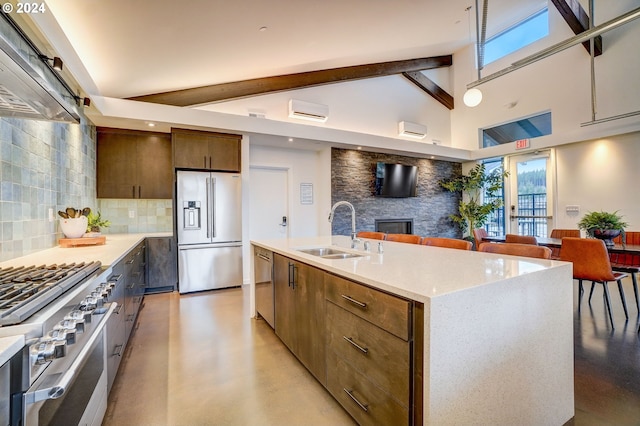 kitchen with sink, tasteful backsplash, a center island with sink, high quality appliances, and beam ceiling