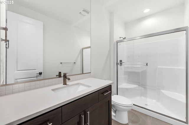 bathroom with a shower with door, vanity, tile patterned floors, and toilet