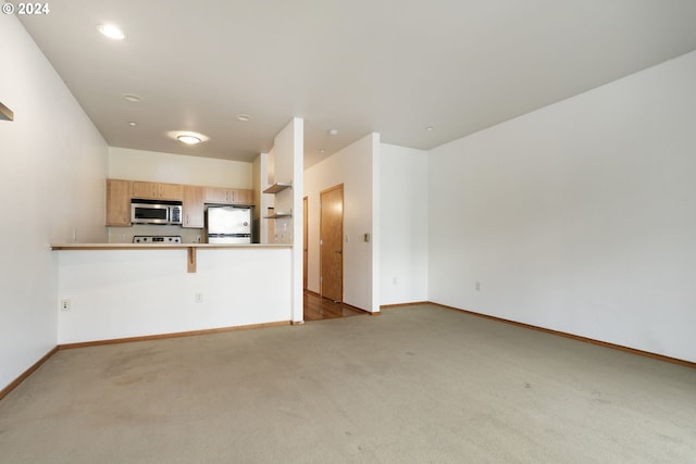 interior space featuring a breakfast bar, white fridge, kitchen peninsula, and light carpet