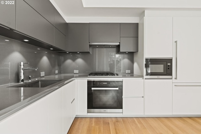 kitchen with a sink, gas cooktop, black microwave, oven, and extractor fan