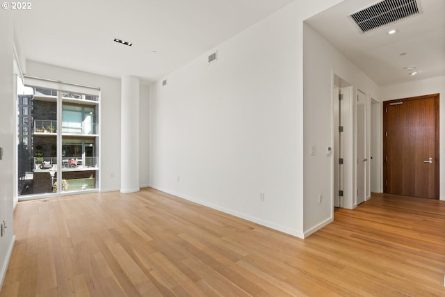 empty room with baseboards, visible vents, and light wood finished floors