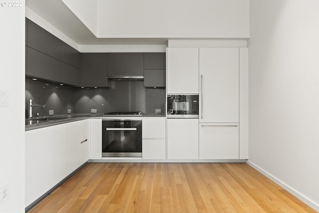 kitchen featuring light wood-style floors, white cabinets, a sink, modern cabinets, and oven