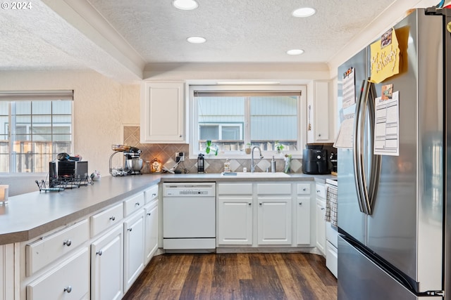 kitchen with white cabinetry, sink, a wealth of natural light, dark hardwood / wood-style flooring, and white appliances