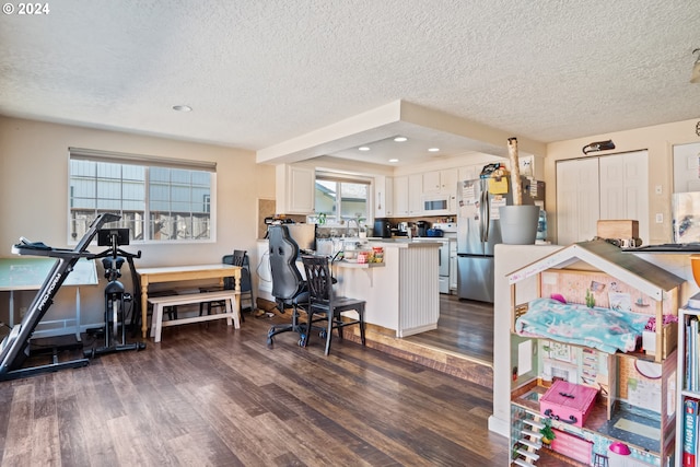 interior space featuring a kitchen bar, dark hardwood / wood-style flooring, white cabinetry, and plenty of natural light