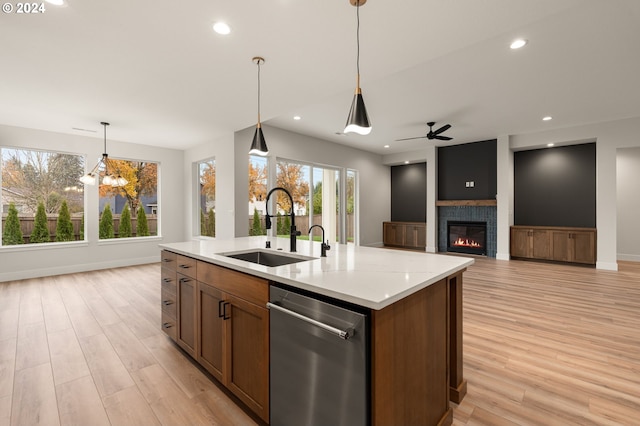 kitchen with sink, hanging light fixtures, an island with sink, ceiling fan with notable chandelier, and light wood-type flooring