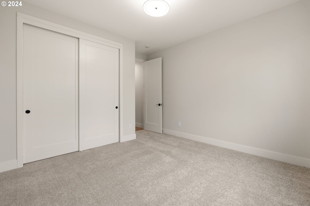 unfurnished bedroom featuring light carpet and a closet